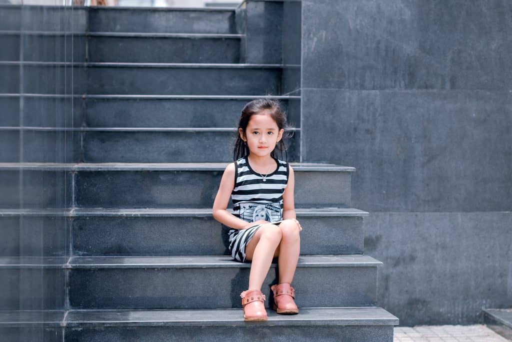 signs of autism.  a girl is sitting on a set of stairs.