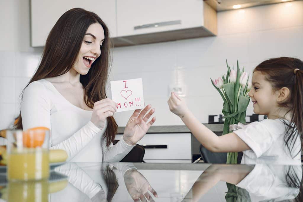 Autism Language Development Activities this image shows a child and her mom holding a card with I love mom written on it