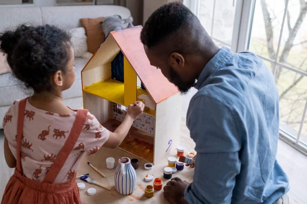 Power Struggles With Kids this image shows a father painting a toy house with his daughter