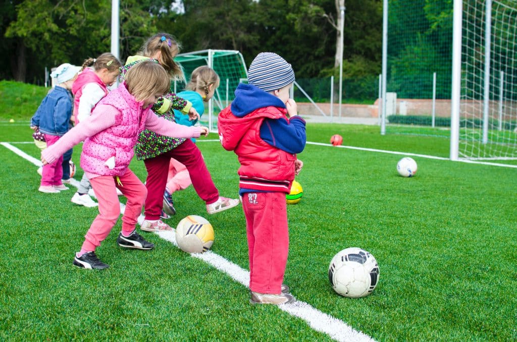 Autism and understanding social cues - a group of children play soccer, with one child standing stationary in the foreground.