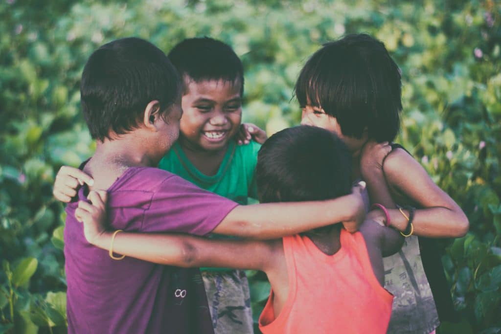 Autism and understanding social cues - a group of four children hug each other in a circle.