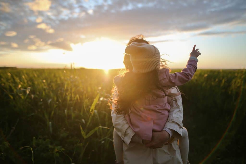 If I have autism will my child have it? A mother holds her baby out in a field.