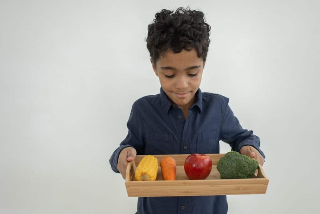 child forgets things learned. A young boy hold healthy food that he will eat in order to promote good memory.