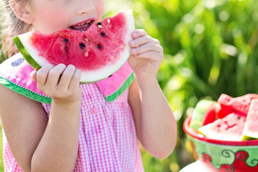 foods to avoid adhd child. A young girl eats watermelon to help with her adhd.