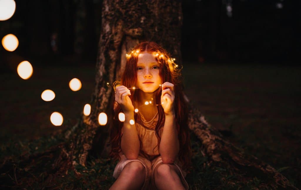 Autistic people show empathy as seen here with a girl sitting by a tree with dynamic lighting and red hair.