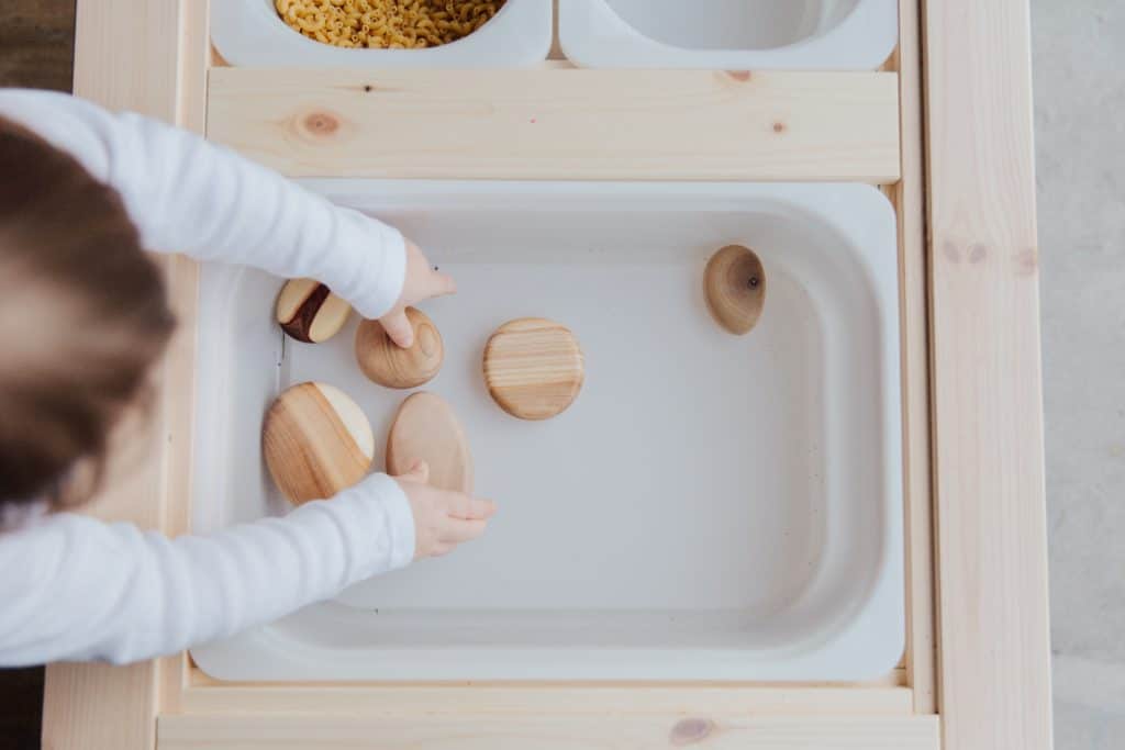 Sensory sensitivities can mean children want to experience more of certain textures and objects like this child who is playing with wooden shapes.