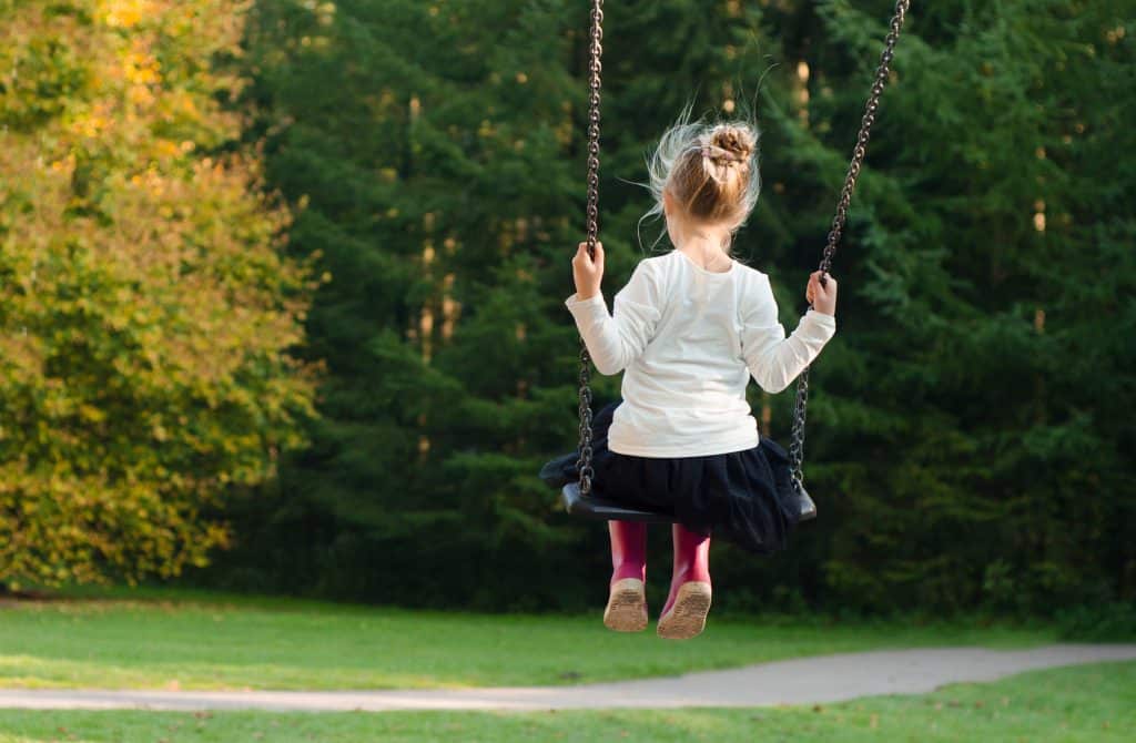 ADHD and rejection sensitivity: A young girl swings on a swing in a park.
