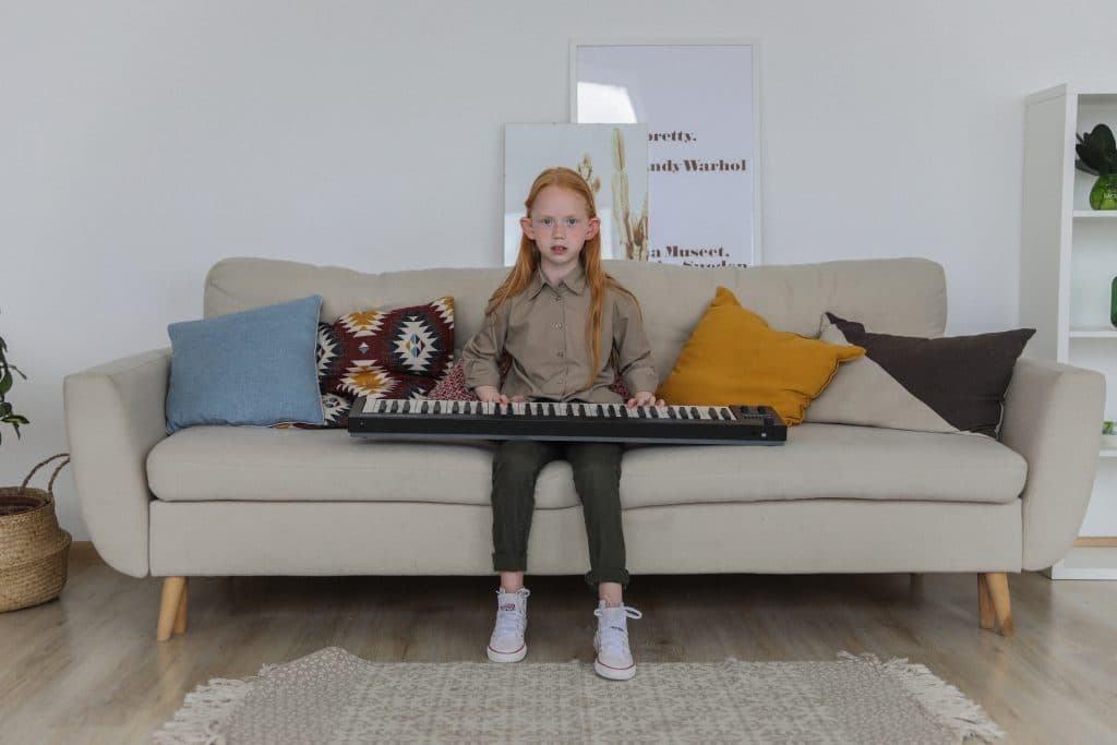 benefits of playing a musical instrument little boy playing keyboard on couch