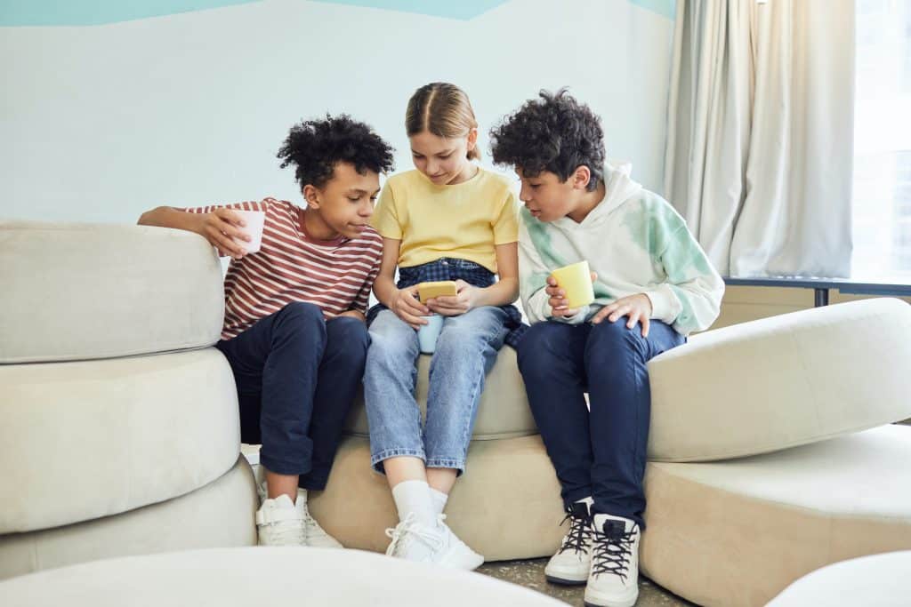 dangers of tiktok. 3 kids look at a phone together.