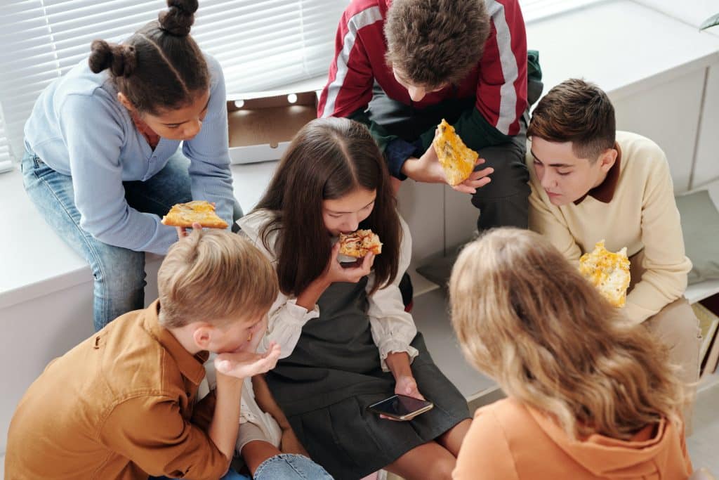 iep high school. a group of friends watch a video while eating pizza.