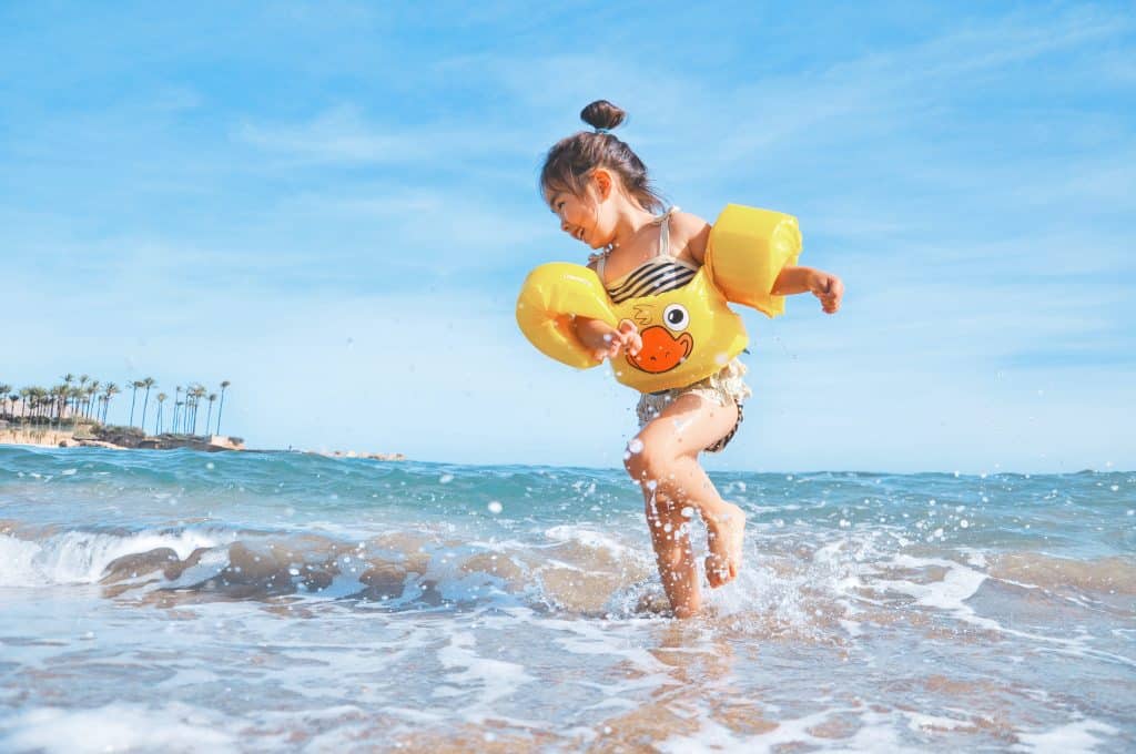 Can you treat ADHD without medication? A kid uses physical activity to use up her energy. A girl plays in the water at the beach while she wears yellow floaties on her arms.