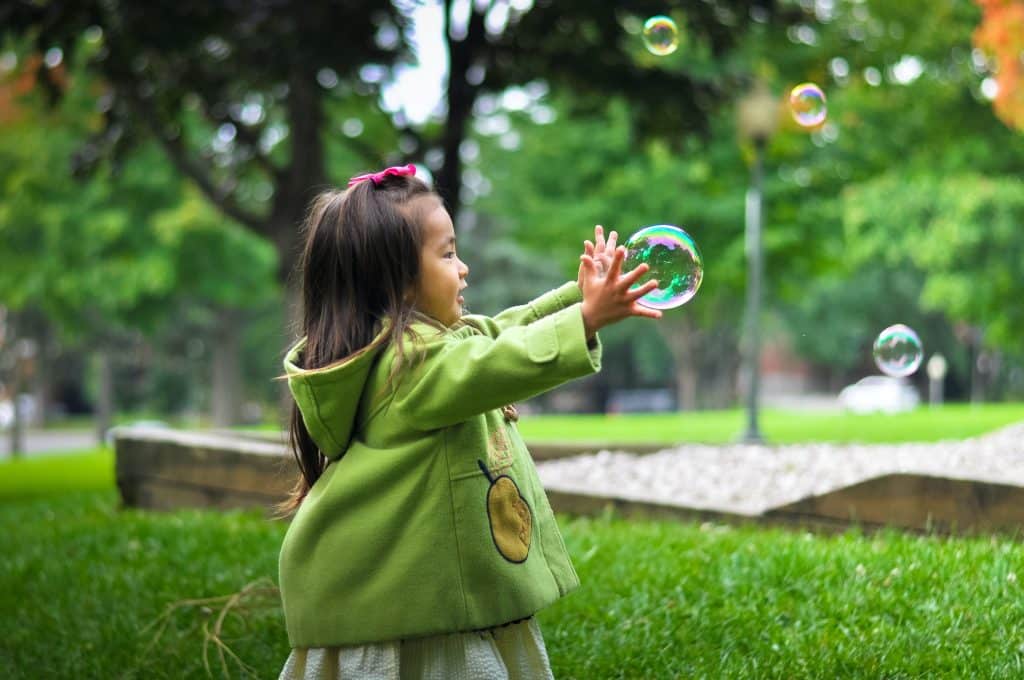 Can you treat ADHD without medication? A child plays with bubbles in a park to drain her energy.