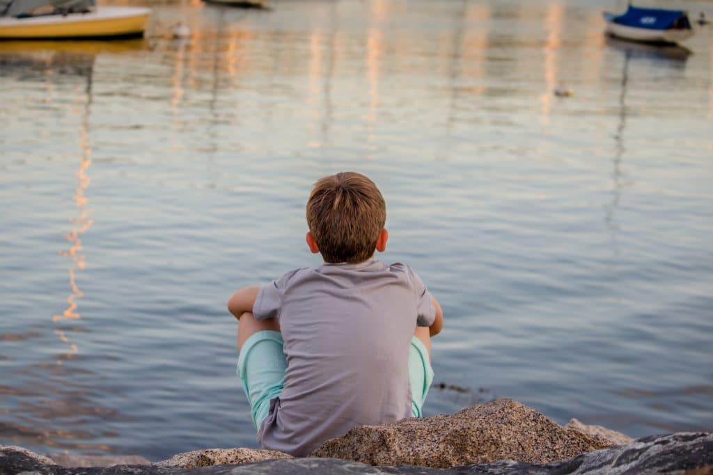 At what age is ADHD diagnosed? Kid sits by the water as he wonders.