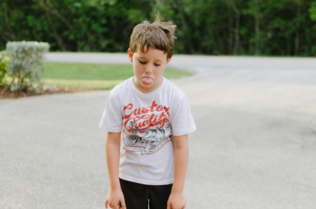What are some ADHD behaviors kids may show? A distracted boy sticks his tongue out during a photoshoot.