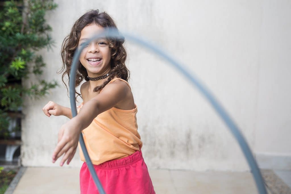 What are some ADHD behaviors that kids show? An energetic girl throws a hula hoop at the camera.