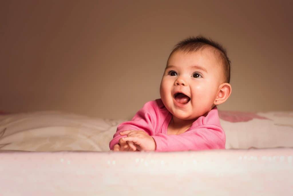 Are you born with ADHD or develop it. a baby dressed in pink is laying in the bed on her stomach. 