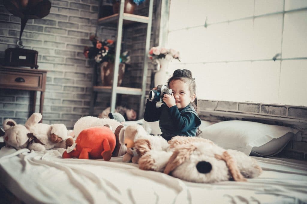 best apps for 1 year olds. A baby is sitting on the bed and using a camera.