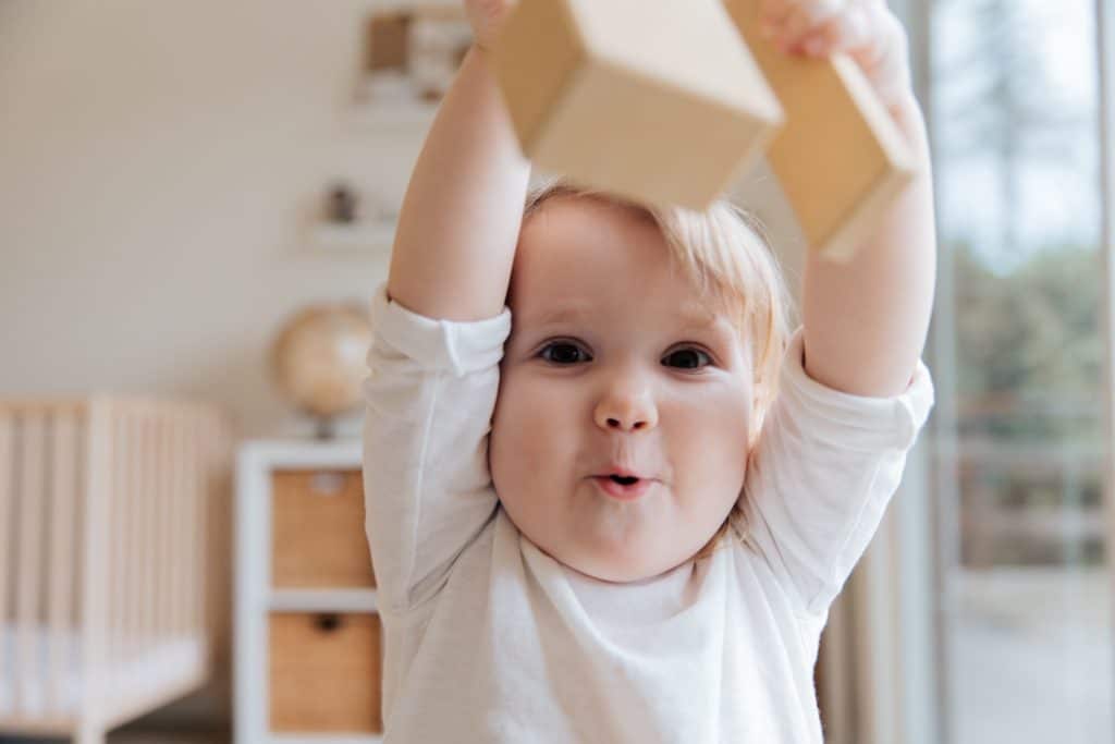 best toys for nonverbal autism. a girl is playing with her blocks and showing the block to someone.