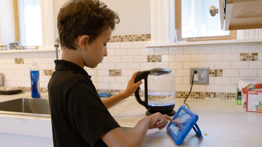 kids chores. A boy is using his Goally device to get his chores done around the house.
