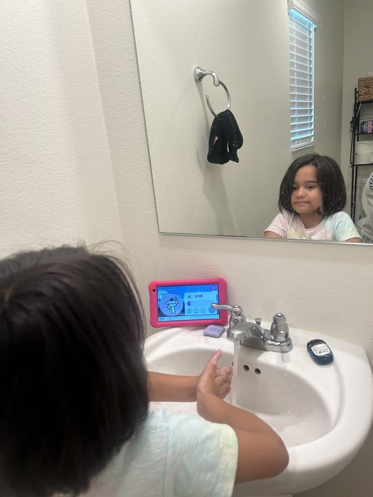 A little girl washes her hands while using her Goally device.