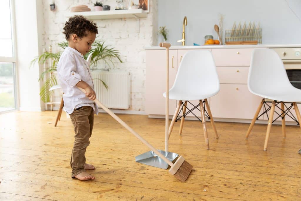 sweep the floor. a boy is sweeping the floor.