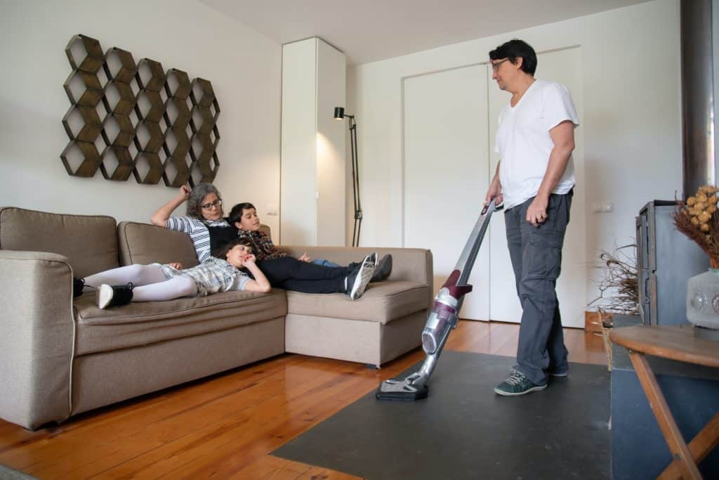 how to vacuum. a dad is teaching his kids how to vacuum.