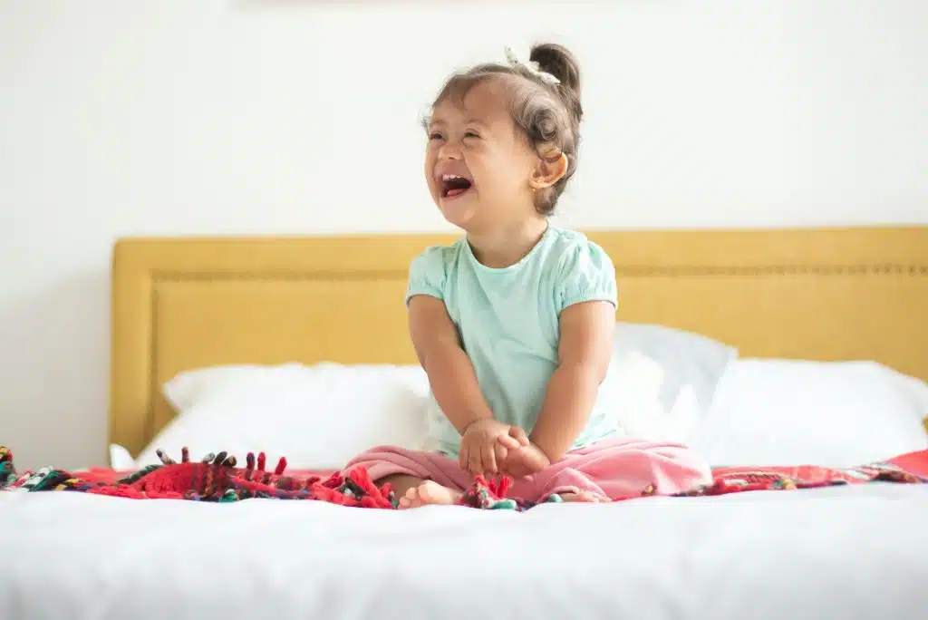 is down syndrome genetic? a girl is laughing while sitting in bed.