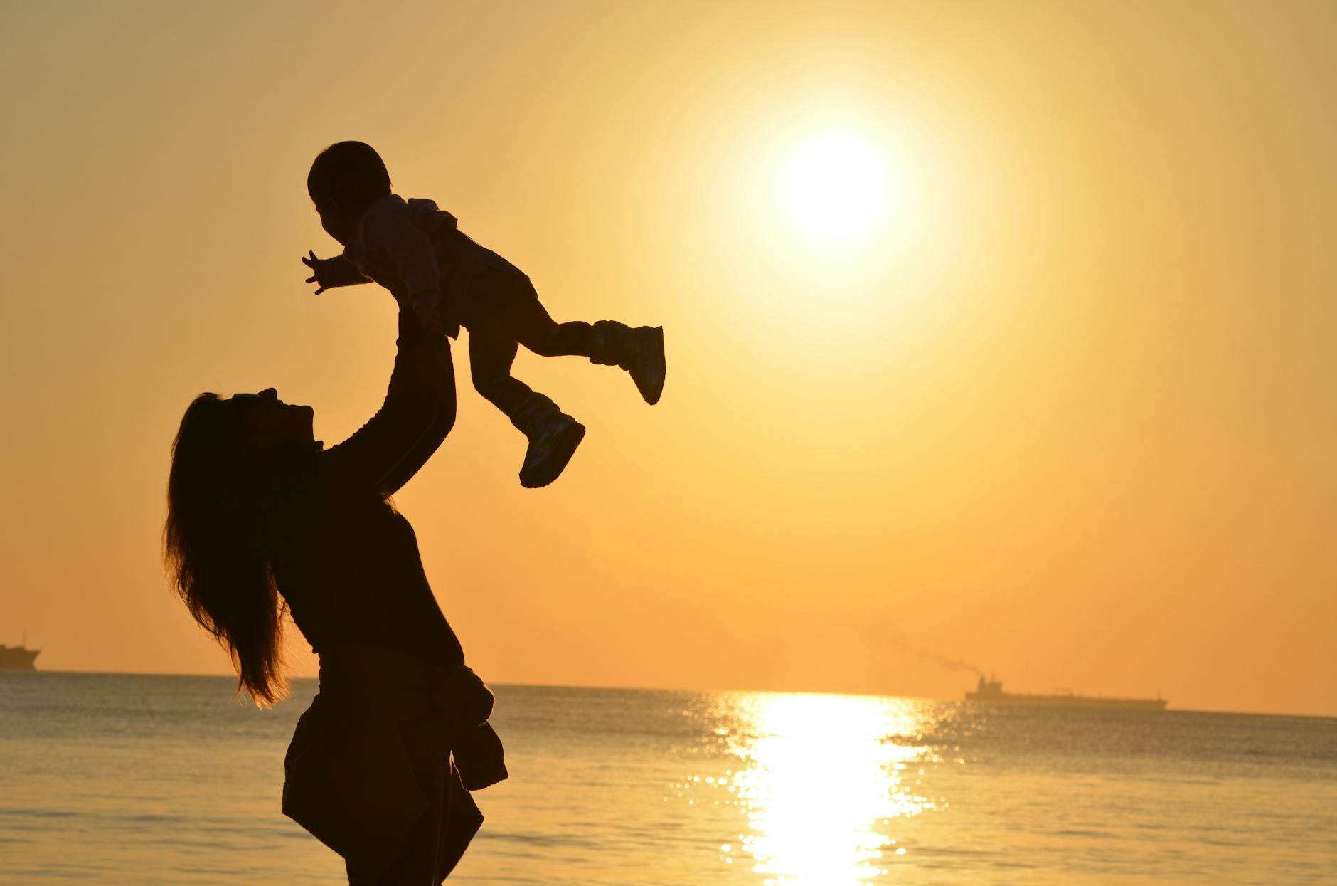 is autism hereditary. silhouette photo of a mother carrying her baby at beach during golden hour