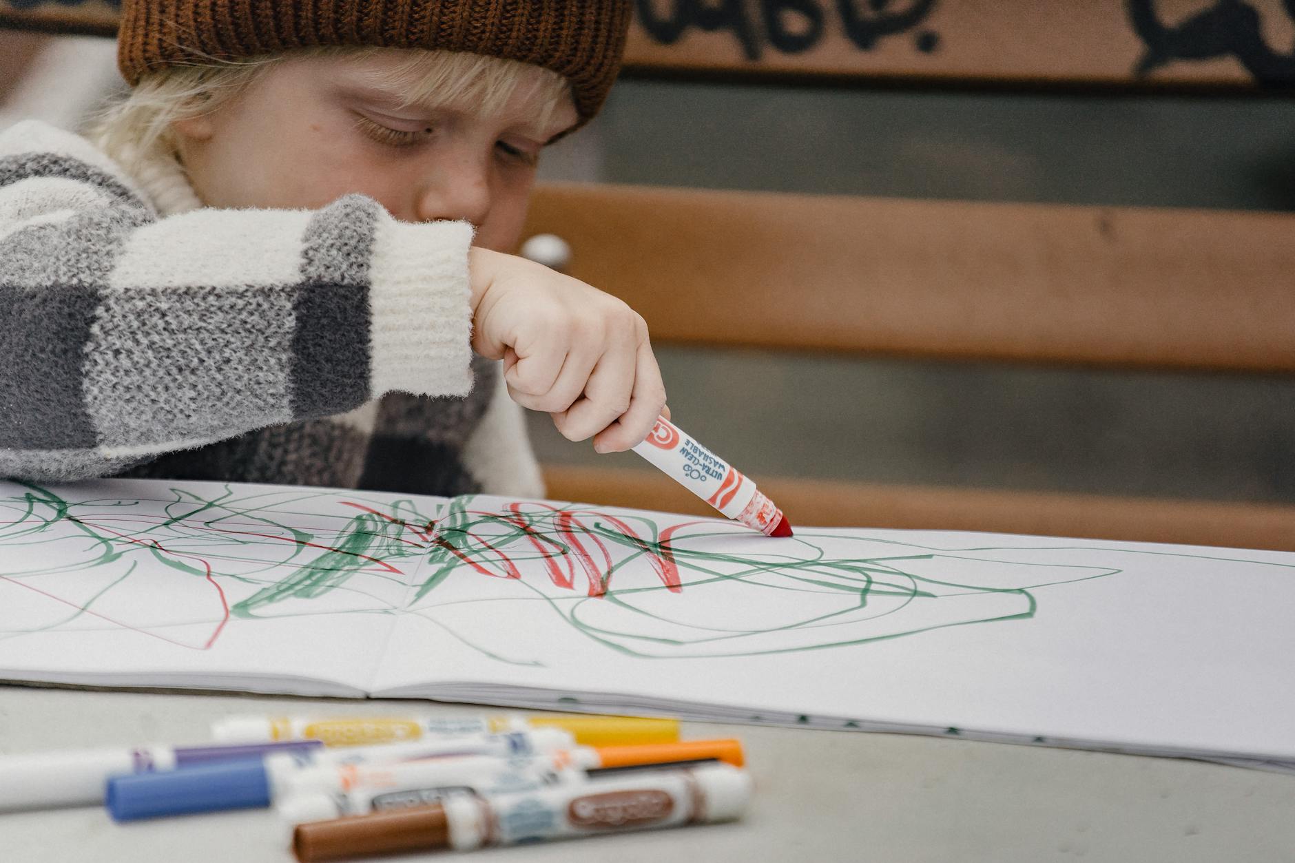 focused little child drawing with markers on paper